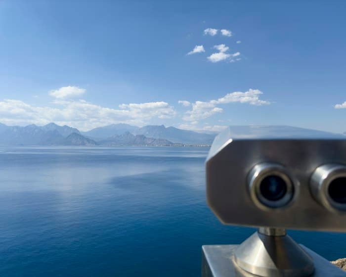 Binoculars trained on a calm sea and distant mountains