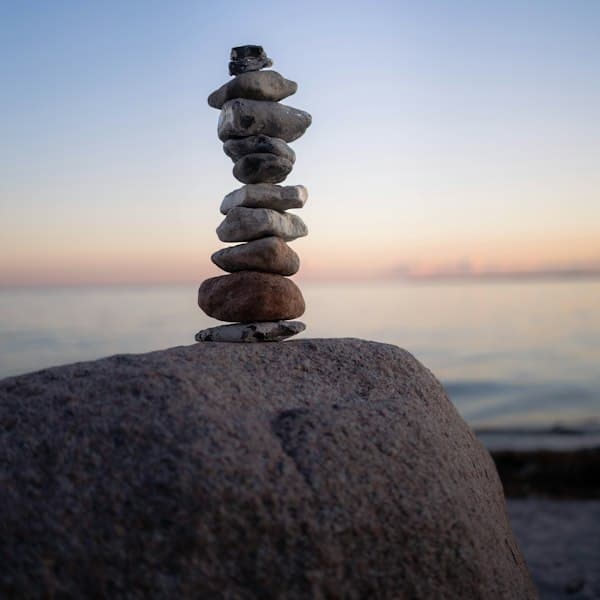 A stack of balanced stones on a rock at sunset