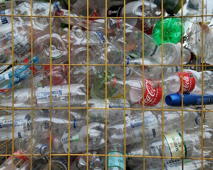 Sorted glass bottles collected in a wire cage for reuse